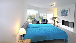 Een moderne slaapkamer met een groot bed, een bureau met lamp, een stoel en een open haard.