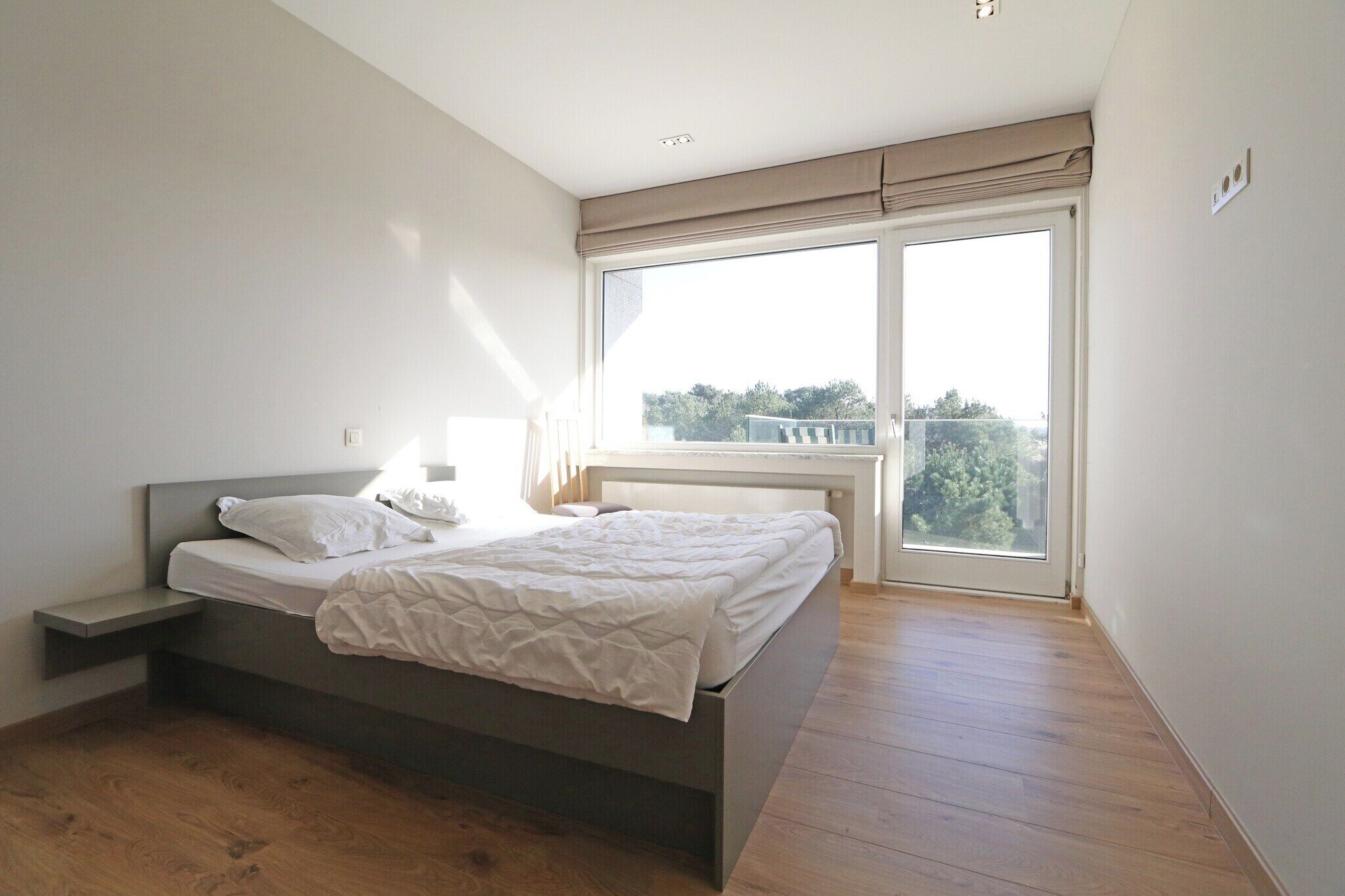 Une chambre à coucher avec un lit, une table de chevet, une fenêtre donnant sur un beau paysage et un luminaire au plafond.