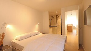Ein Hotelzimmer mit einem Bett, einem Nachttisch und einem durchgegangene Tür erkennbaren Badezimmer.