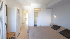Une chambre à coucher avec un lit, une chaise, une petite table et une armoire.