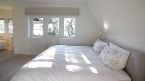 Un dormitorio con una cama grande, una ventana y un baño a la vista.