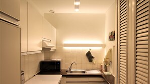 A compact kitchen with white cabinets, a microwave, a sink, and a stove.
