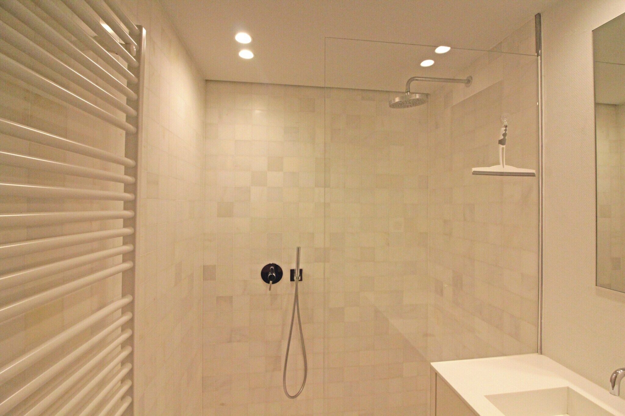 A modern bathroom with a glass shower enclosure, a standalone sink, and a towel rack.