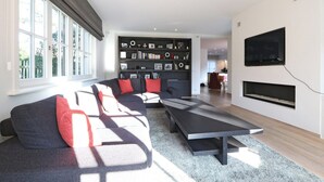 Una sala moderna con un sofá seccional, un televisor de pantalla plana y una chimenea.