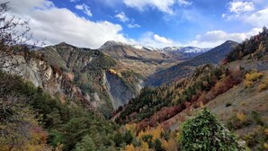 Eine Berglandschaft mit einem Tal, Bäumen im Herbstlaub und einem klaren Himmel.