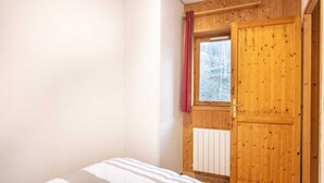 Ein Schlafzimmer mit Bett, Holztür, Fenster und Heizkörper.