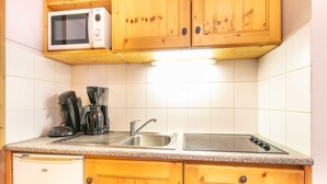 Eine kleine Küche mit Holzschränken, einer Mikrowelle, einem Spülbecken und einem Geschirrspüler.
