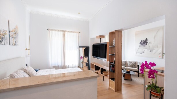 Un salon moderne avec un canapé, un téléviseur et des œuvres d’art accrochées au mur.