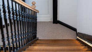 Un escalier en bois avec une rampe en métal noir et une porte blanche en haut.
