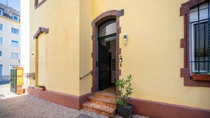 Un edificio amarillo con una puerta negra y unos pocos escalones que llevan a la entrada.