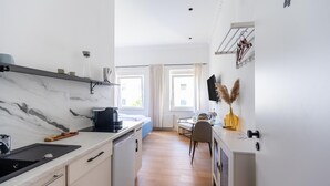 Una cocina compacta con encimera de mármol, cafetera y comedor con mesa y sillas.