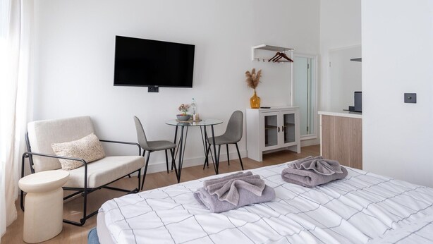 Una habitación de hotel moderna con cama, televisor, escritorio y silla.