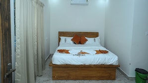 Un dormitorio con cama de madera, ropa de cama blanca y un ventilador de techo.