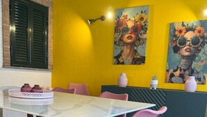 A dining area with a marble table, pink chairs, and a yellow wall with artwork. - Independent villa with free parking space and close to the subway - Rome (Roma)
