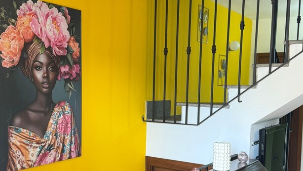 A staircase with a black railing, a wooden cabinet, and a yellow wall with a floral painting. - Independent villa with free parking space and close to the subway - Rome (Roma)