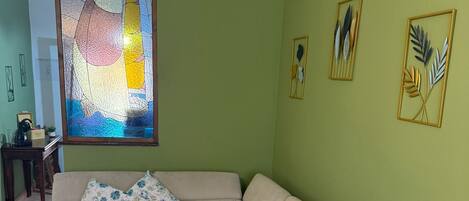 Un salon avec un canapé d’angle beige, une table basse et un tableau représentant un voilier.