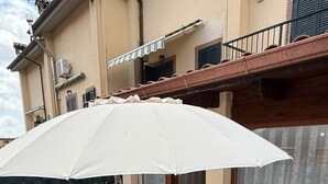 An outdoor patio with a white table and four chairs, a white umbrella, and a trash bin. - Independent villa with free parking space and close to the subway - Rome (Roma)