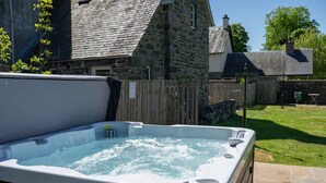 Un jacuzzi en un patio trasero con muros de piedra y valla de madera.