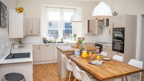 Una cocina moderna con armarios blancos, una isla de madera y un fregadero de acero inoxidable.