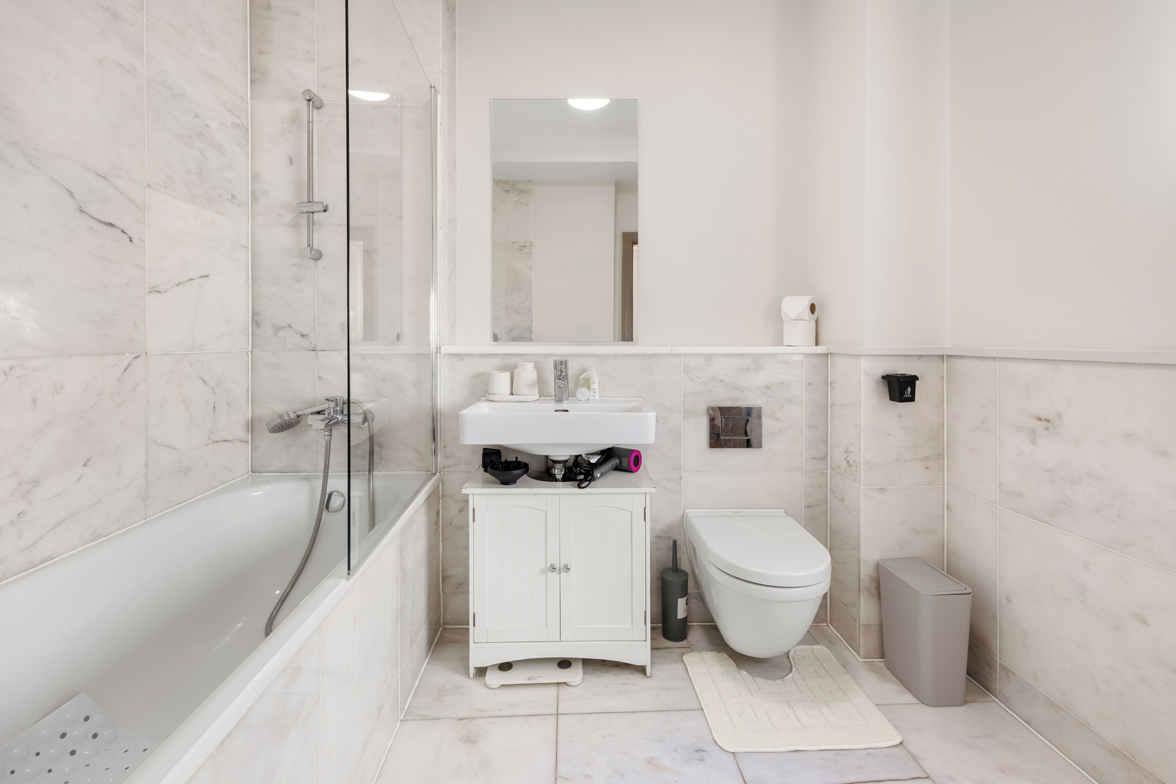 Een moderne badkamer met een douchecabine van glas, een witte wastafel en een toilet.