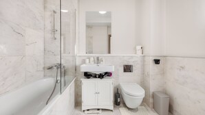 Ein modernes Badezimmer mit einer gläsernen Duschkabine, einem weißen Waschbecken und einer Toilette.