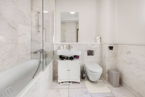 A modern bathroom with a glass-enclosed shower, a white sink, and a toilet.