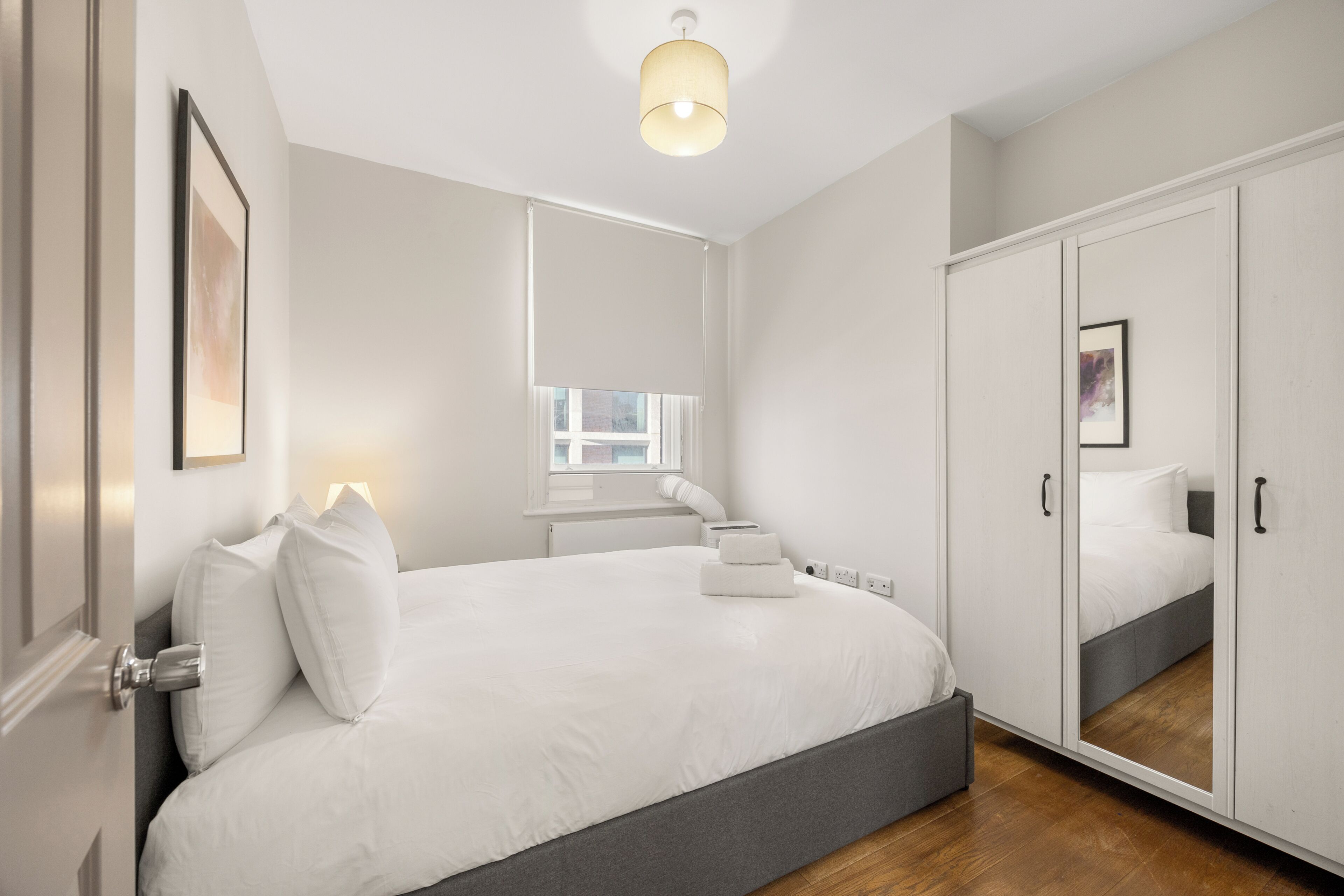 Een moderne slaapkamer met een groot bed, een garderobe en een trap naar een verdieping.