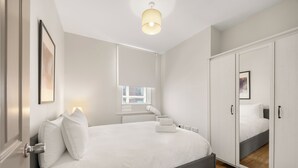 Ein modernes Schlafzimmer mit einem großen Bett, einem Kleiderschrank und einer Treppe, die zu einer oberen Ebene führt.