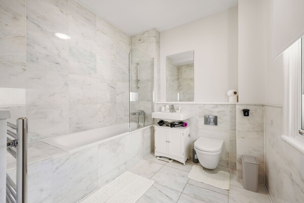 A modern bathroom with a glass-enclosed shower, a white toilet, and a sink with a mirror above it.