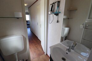 A bathroom with a white toilet, a sink with a mirror, and a towel rack.
