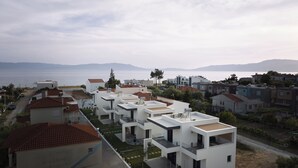 Eine Küstenwohngegend mit modernen weißen Gebäuden, freiem Blick auf das Meer und fernen Bergen.