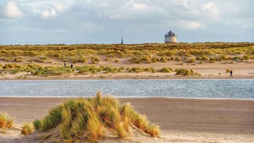 Een strand met duinen en een waterpartij.