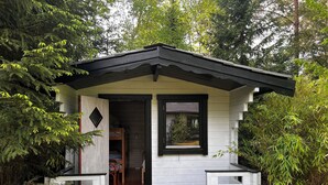 A small, single-story cabin with a front porch, a window, and a door leading to an interior space.