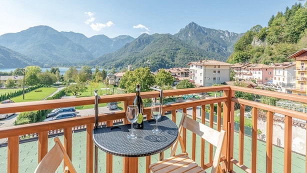 Un balcon avec une table, deux chaises et une bouteille de vin.