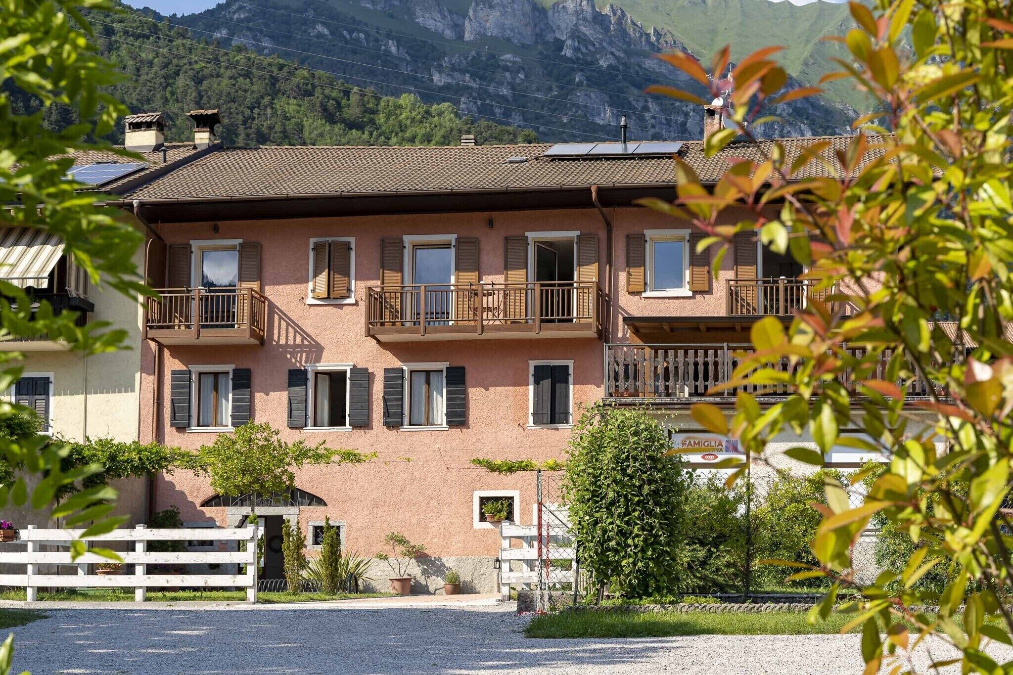 A multi-story building with balconies, a gravel driveway, and a mountain backdrop.