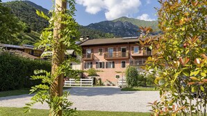 A multi-story building with balconies, surrounded by greenery and mountains. - Apartment in Mezzolago by Lake Ledro (Mezzolago (TN))