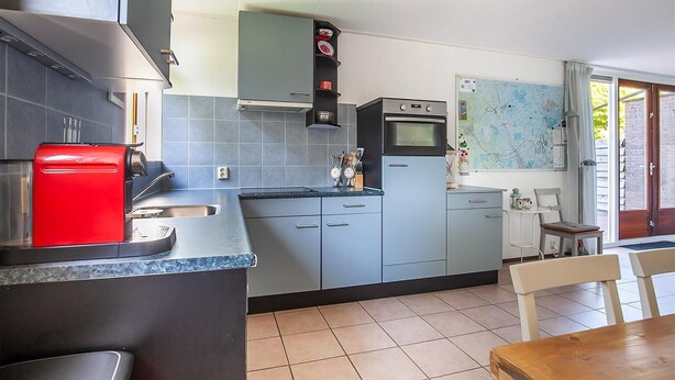 A compact kitchen with grey cabinets, a red coffee machine, and a map on the wall. - Holiday Home in Grou with Whirlpool & Terrace (Grou)