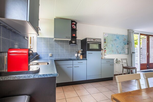 A compact kitchen with grey cabinets, a red coffee machine, and a map on the wall.