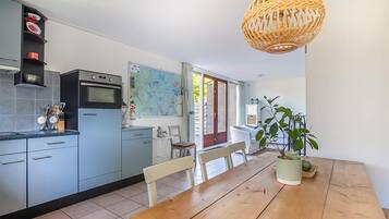 Une cuisine moderne avec des meubles bleus, une table à manger en bois et une carte accrochée au mur.