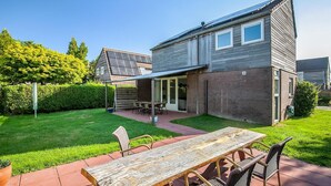 A modern house with a patio, a dining table, and chairs. - Holiday Home in Grou with Whirlpool & Terrace (Grou)