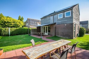 A modern house with a patio, a dining table, and chairs.