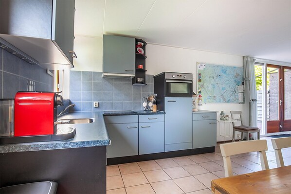A compact kitchen with grey cabinets, a red coffee machine, and a map on the wall. - Holiday Home in Grou with Whirlpool & Terrace (Grou)