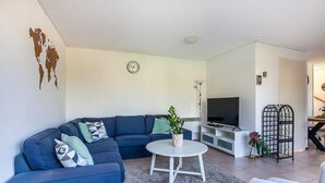 A living room with a blue sofa, a white coffee table, and a TV stand. - Holiday Home in Grou with Whirlpool & Terrace (Grou)