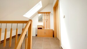 A staircase with wooden handrails leading to a room with a built-in wardrobe and a mirror.