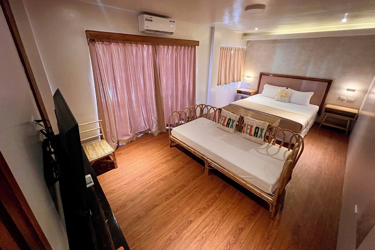 Ein Hotelzimmer mit Bett, Schreibtisch, Stuhl, Klimaanlage und Vorhängen.