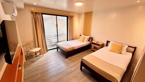 A hotel room with two beds, a desk, a chair, and a large window with curtains. - La Palme (El Nido)
