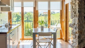 Une cuisine moderne dotée d’une grande fenêtre, d’un plancher en bois et d’un coin repas avec une table et des chaises.