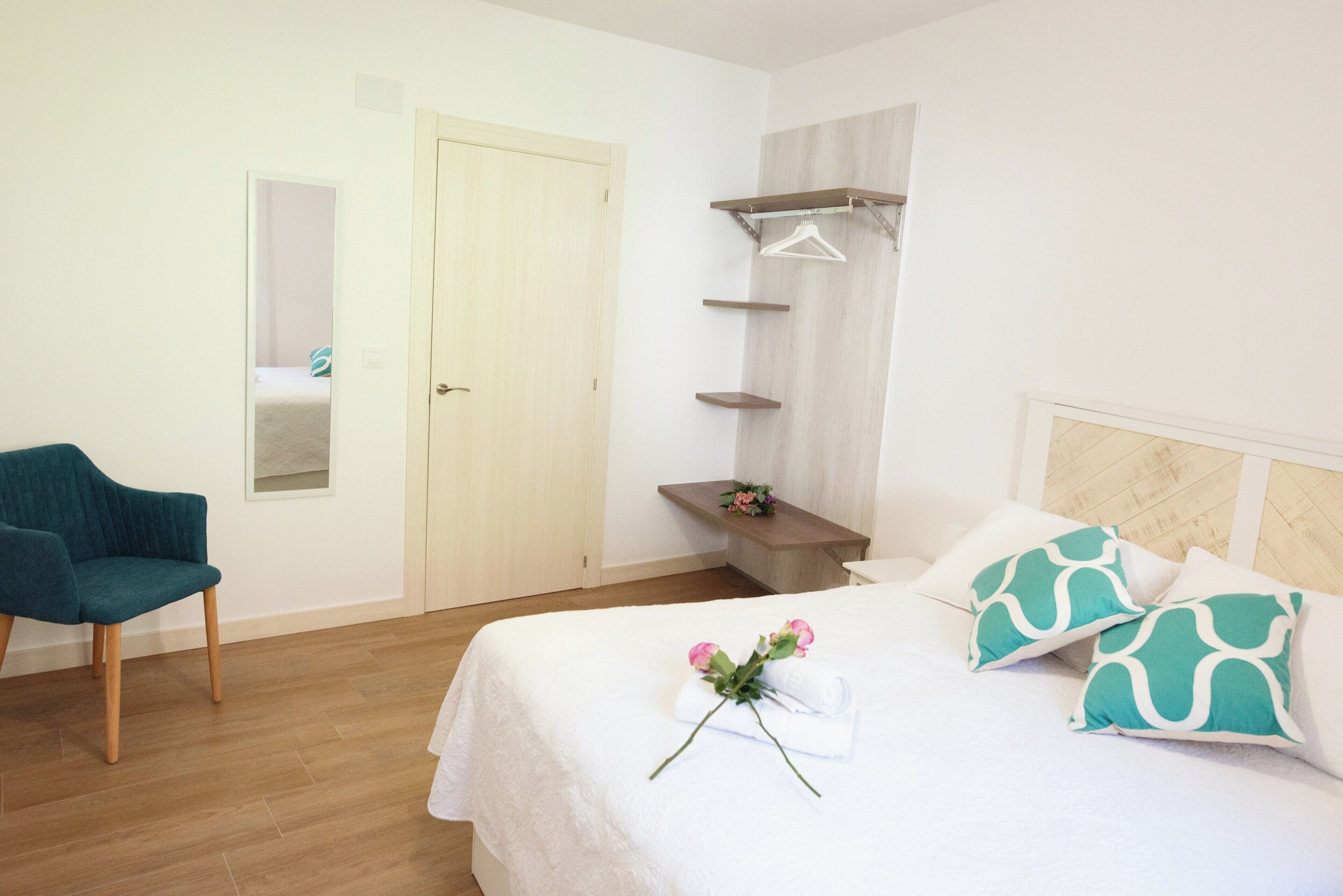 Une chambre à coucher avec un lit, une chaise, une armoire et un miroir.