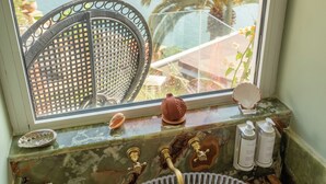 A bathroom with a large window overlooking a beach, a marble sink, and various toiletries. - Dar Baraka (Rabat)