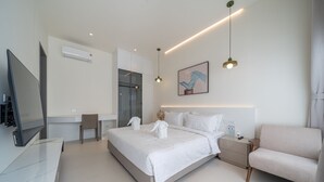 Ett modernt hotellrum med en stor säng, en TV, ett skrivbord och en soffa.